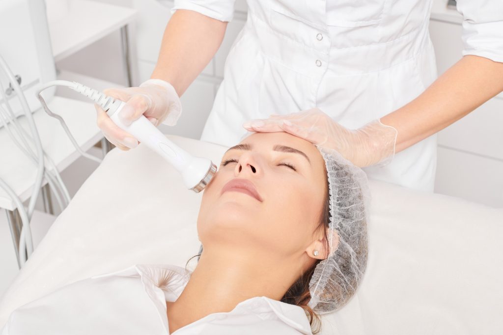 Beautician makes ultrasound skin tightening for rejuvenation woman face using phonophoresis